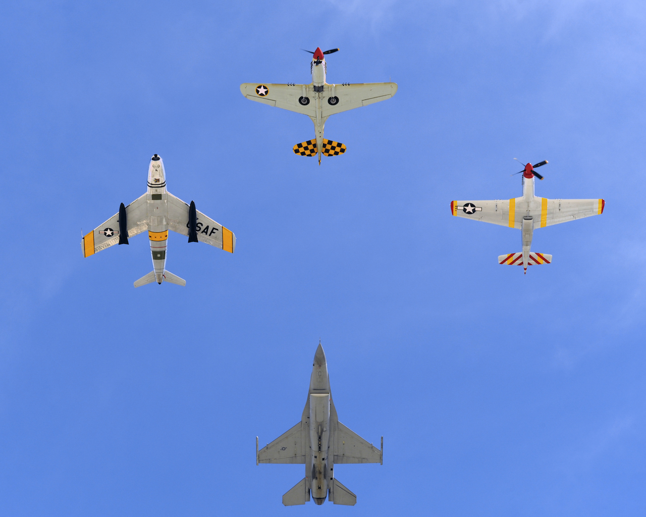 A U.S. Air Force F-16 Fighting Falcon (bottom) joins in formation with a P-40 Warhawk (top), P-51 Mustang (right), and a F-86 Sabre Jet (left) over Davis-Monthan Air Force Base, Ariz., during Heritage Flight Training Course March 2, 2014. During the course aircrews practiced ground and flight training to allow civilian pilots of historic military aircraft and current Air Force fighter pilots to safely fly in formations together, in preparation for the upcoming Open House. (U.S. Air Force photo by Airman 1st Class Chris Massey/ Released) 