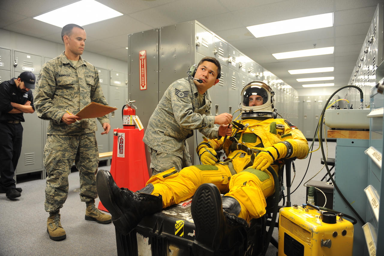 Staff Sgt. Timothy Dayrit (center), and Staff Sgt. Joseph Kennedy (left), 9th Physiological Support Squadron full-pressure suit technicians perform pre-flight full-pressure suit maintenance for Capt. Travis, 99th Reconnaissance Squadron U-2 pilot, Sep. 19, 2015, at Joint Base Andrews, Maryland. The full-pressure is worn by U-2 Dragon Lady pilots who frequently fly at the edge of space. (U.S. Air Force photo by Senior Airman Bobby Cummings/Released)