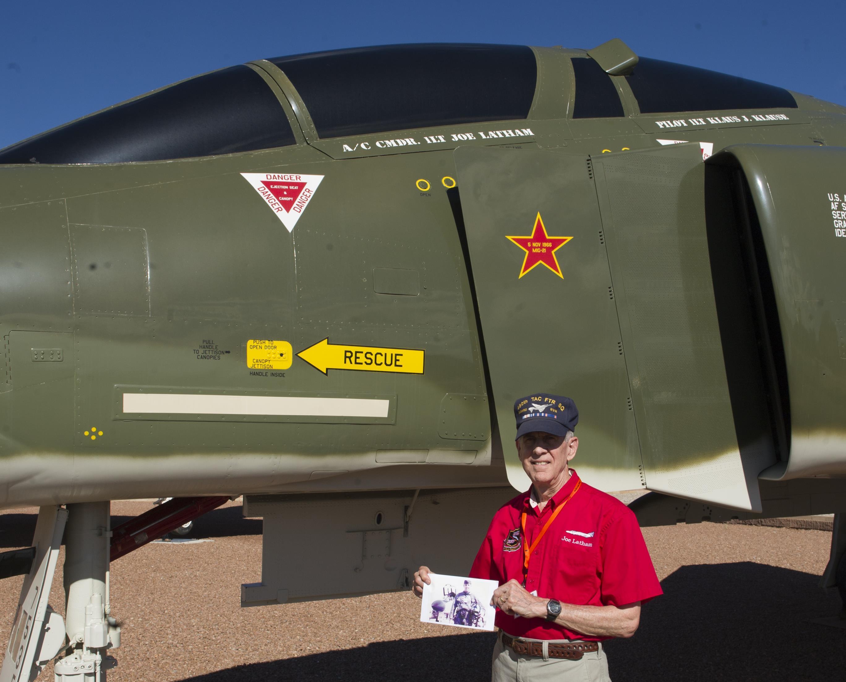 Col. (Ret.) Joe Latham, previously an F-4 Phantom pilot from Holloman Air Force Base, N.M., poses for a picture with an old photo as a first lieutenant in 1966, next to an F-4 adorned with his name Sept. 13, 2016, at Heritage Park, Holloman AFB. Latham’s visit was part of the annual Phantom Society Tour where 160 aircraft enthusiasts, including veterans and non-veterans with aviation backgrounds, toured The tour included an F-16 Fighting Falcon static display and briefing, travel to Holloman’s High Speed Test Track, the opportunity to view QF-4 Phantom IIs and F-16s in flight, and a visit to the base’s heritage park to view static displays of various aircraft historically stationed at Holloman AFB. (U.S. Air Force photo/Master Sgt. Matthew McGovern)