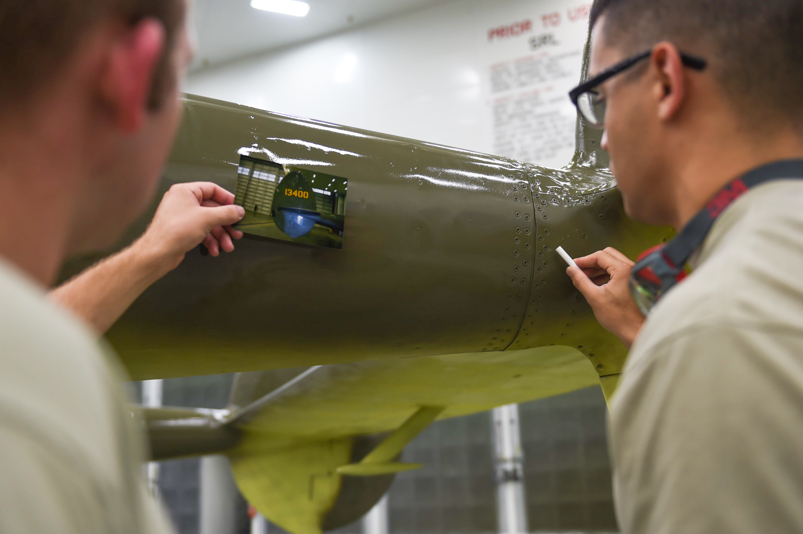 Air Force Senior Airman Kurtis Steinecke (left) and Airman 1st Class Jonathan Torres-Zaya put the final touches on the P-38G Lightning before it can be returned to the Heritage Park at Joint Base Elmendorf-Richardson, Alaska, July 20, 2017. (Photo by Staff Sgt. Sheila deVera)
