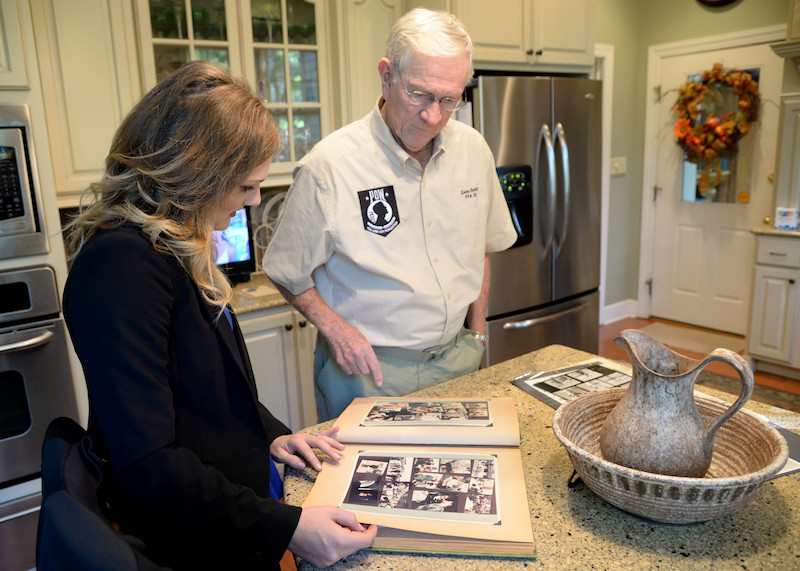 Retired Lt. Col. Richard “Gene” Smith, former 50th Flying Training Squadron Commander, shows Courtney Cox, editor of Town and Gown magazine, documents and photos of when he was a prisoner of war, Oct. 17, 2017, in his home in West Point, Mississippi. Smith was shot down Oct. 25, 1967, and spent five and a half years as a POW. (U.S Air Force photo by Airman 1st Class Beaux Hebert)