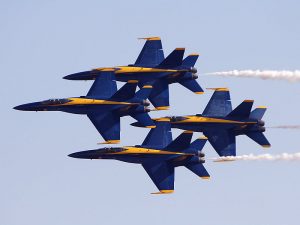 The Blue Angels F/A-18 Hornets fly in their signature tight diamond formation, maintaining a hair-raising 18-inch wing tip to canopy separation.