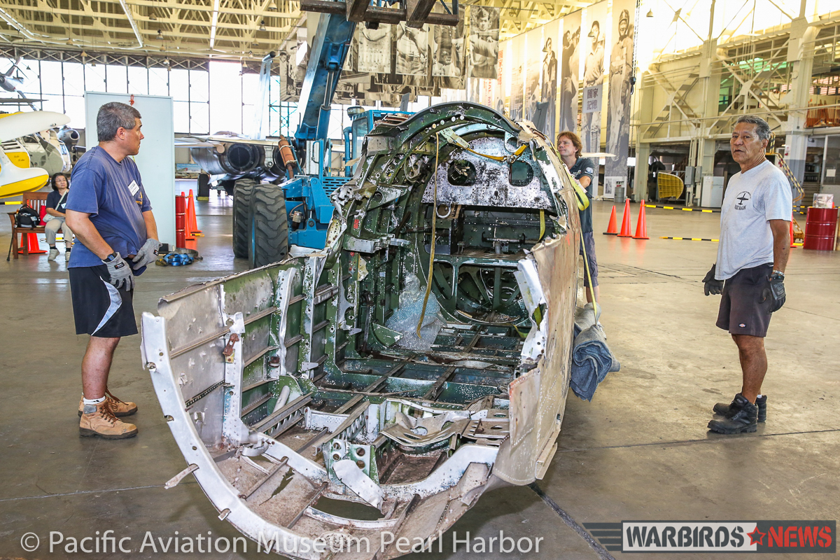 A closer look inside the fuselage/cockpit section looking from the rear as museum staff move the parts into position. (photo via Pacific Aviation Museum Pearl Harbor) 