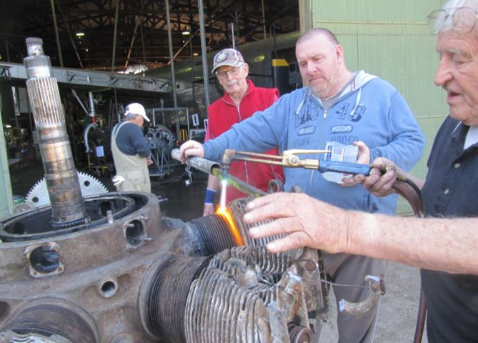 Volunteers working on one of the Oxford's engines. They are heating and cooling the cylinder barrel in an attempt to separate it from the engine core for servicing. (photo via B-24 Liberator Memorial Fund)