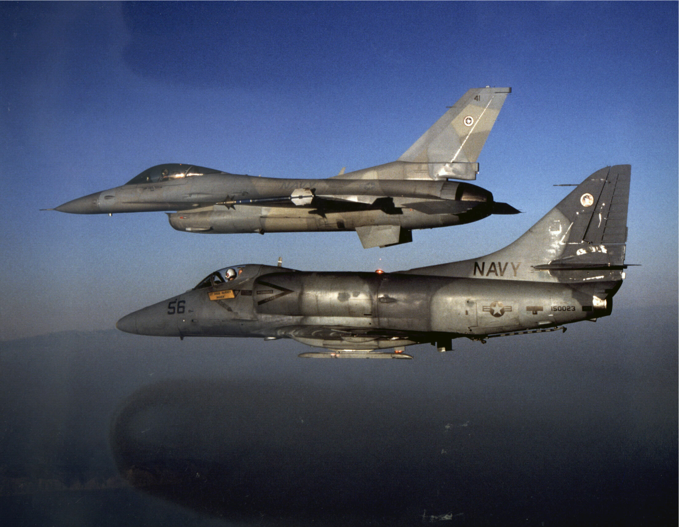 An A-4E Skyhawk (foreground) and F-16N Viper, both assigned as aggressor aircraft at the Navy Fighter Weapons School (TOPGUN) pictured in flight near San Clemente Island off the coast of California in 1989. (Robert L. Lawson Photograph Collection, National Naval Aviation Museum)