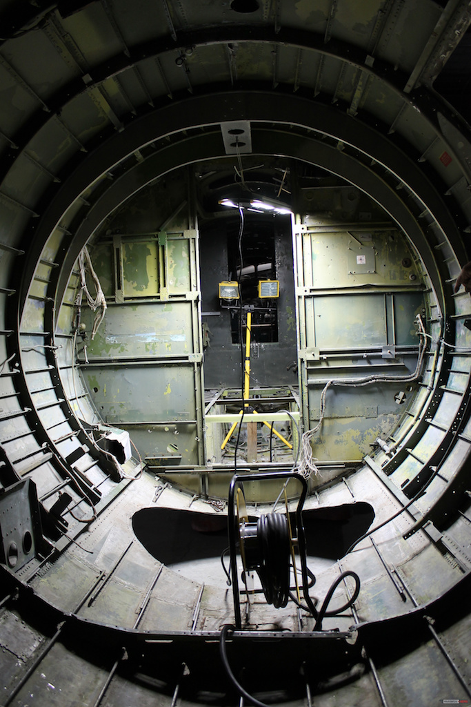Inside the waist section looking forward. The yellow light stand is in the radio room. The fuselage is designed to be separated at a production break just behind the wall or bulkhead separating the radio room from the waist compartment. The hole in the floor is where the ball turret was located. ( Photo via Museum of Aviation Warner Robins AFB) 