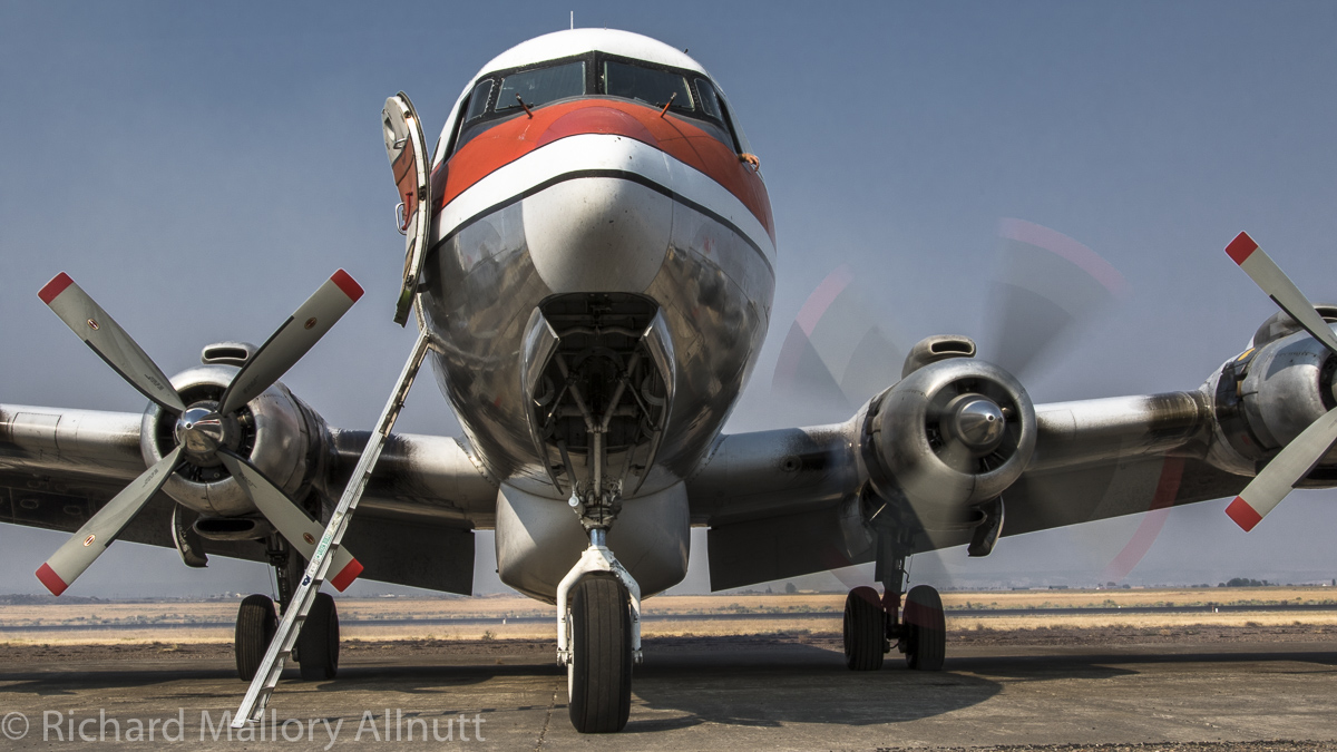 A Douglas DC-7 Air Tanker receives some attention to its number two engine, which the mechanics fired up during the morning's airport activities. (photo by Richard Mallory Allnutt)