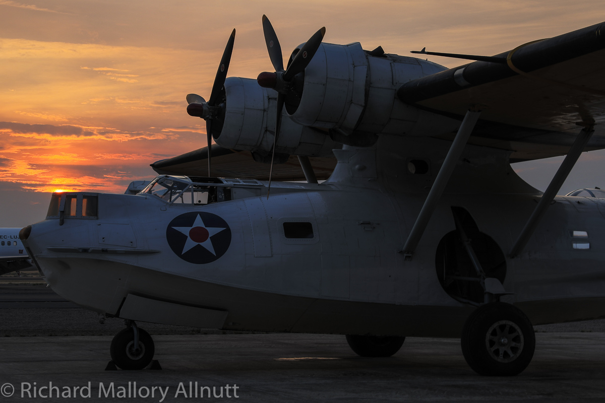 The setting sun silhouette's the Erickson Aircraft Collection's PBY Catalina at the end of today, while the air show party carried on inside the hangar. (photo by Richard Mallory Allnutt)