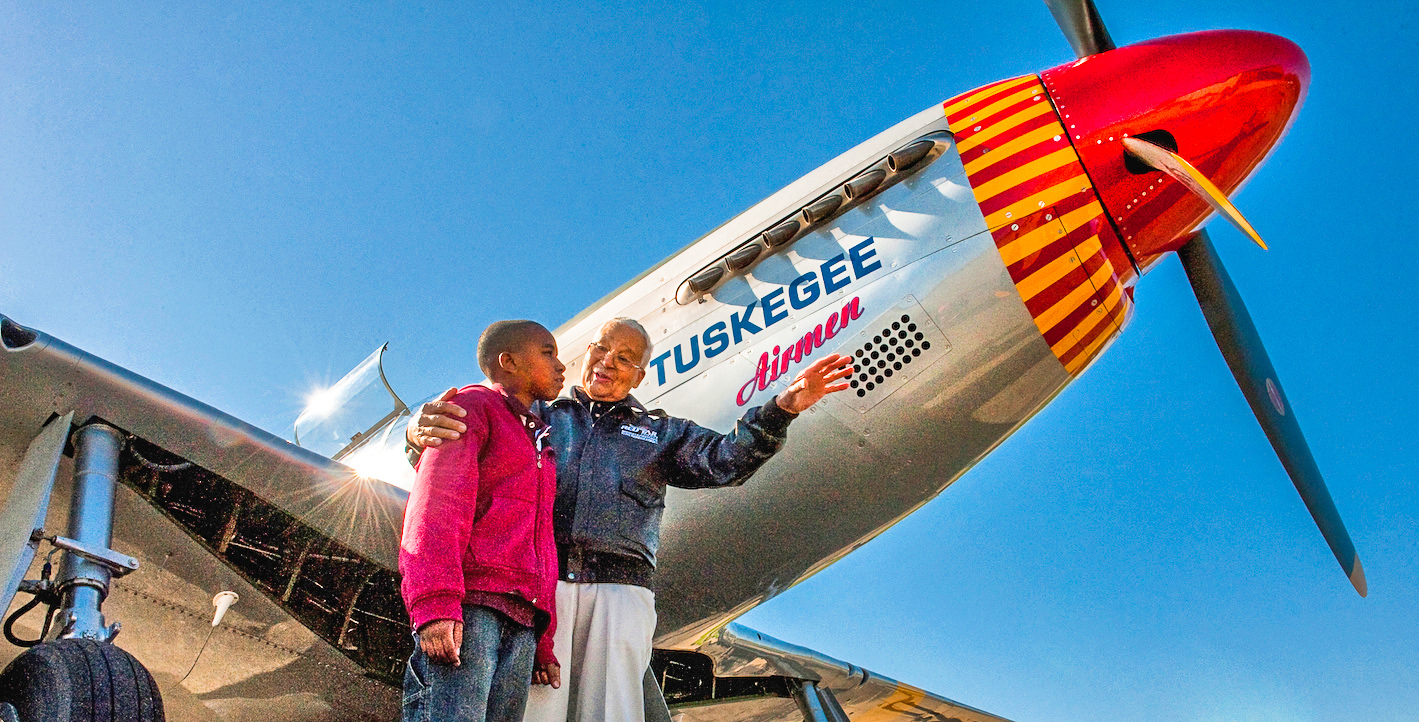 Tuskegee Airman Colonel Charles McGee with a young boy and the Red Tail Squadron's P-51C. (photo via CAF) 