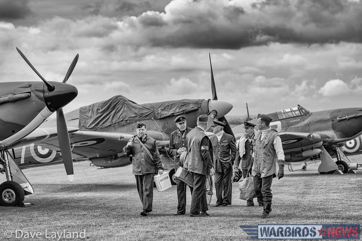 RAF re-enactors walk on the flight line near the Hawker Hurricanes. (photo by Dave Layland)