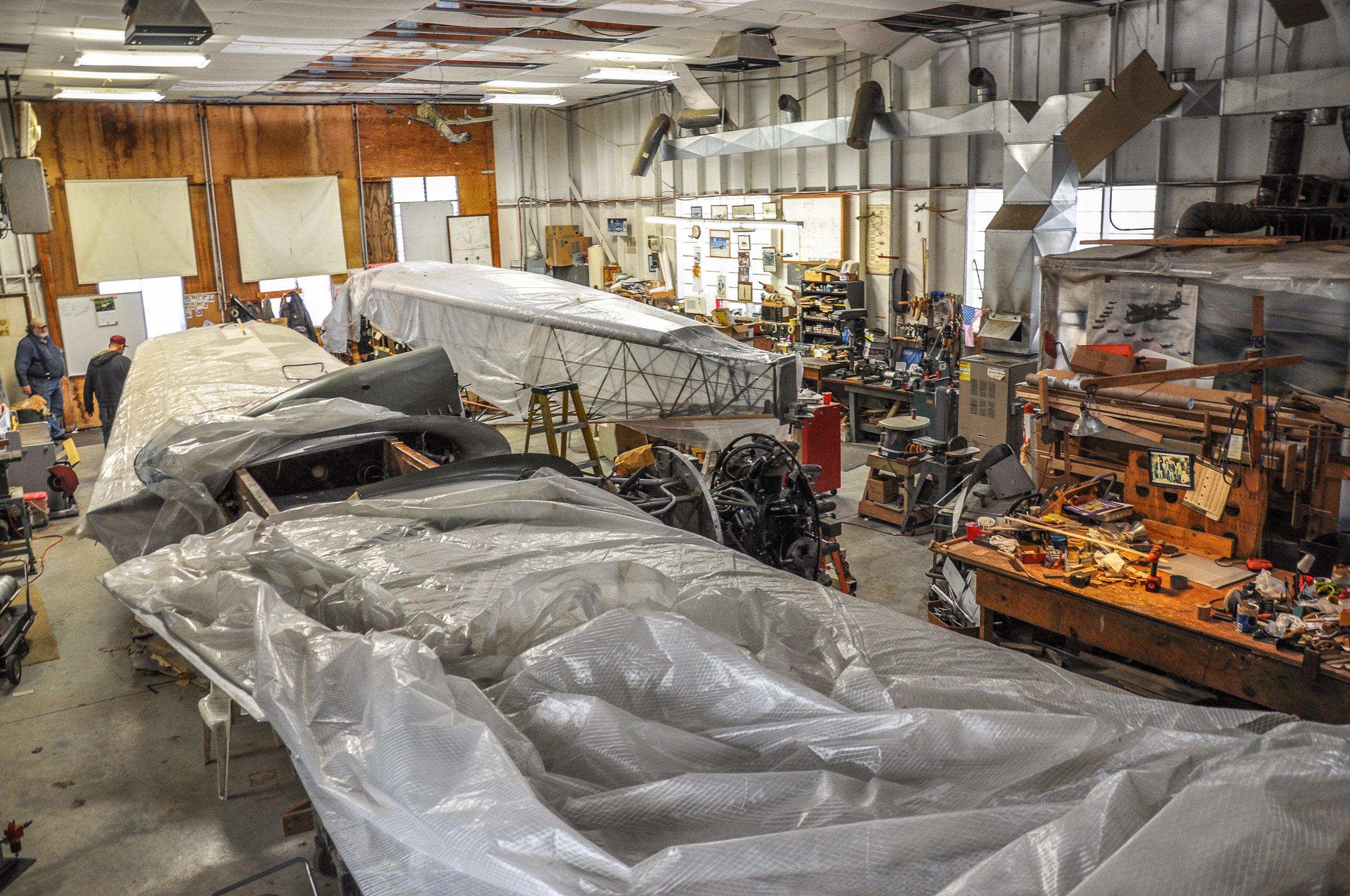 An image inside of the restoration shop.  The wings and fuselage are covered with plastic tarps in the event that the roof started to leak. (David Cohen photo)