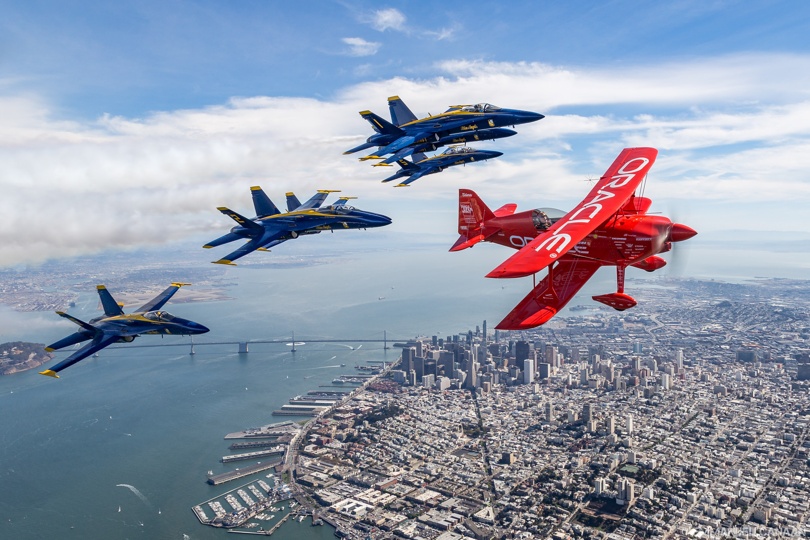 The Blue Angels aerial demonstration team forms up on Sean D. Tucker in his unique Oracle Challenger III aerobatics ship over San Francisco. (photo by Emmanuel Canaan)