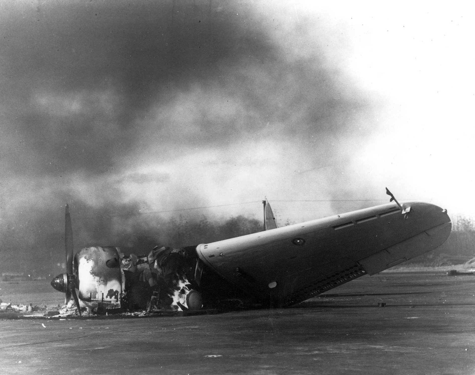 The remains of a Douglas SBD Dauntless dive-bomber burns on Ewa's ramp on Dec. 7, 1941.