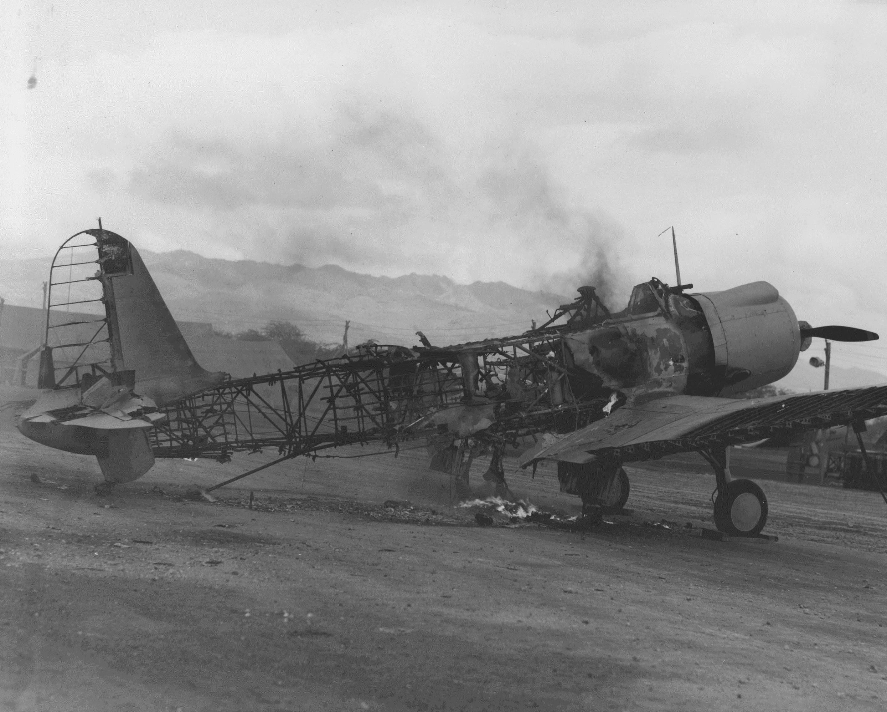 A Vought SB2U Vindicator dive-bomber, still smoldering, shortly after the Japanese attack on Ewa and Pearl Harbor.