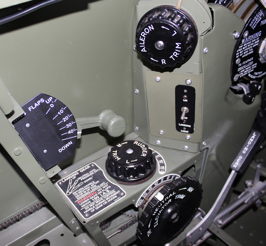 The left cockpit flap handle, aileron trip, landing light switch, rudder trim, elevator trim and gear handle. (Photo via Tom Reilly)