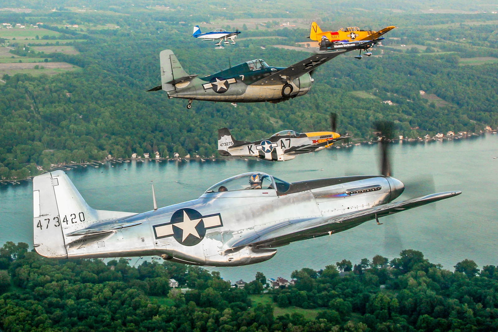 A mighty formation over the Genesee Valley featuring Andrew McKenna in his P-51D Mustang alongside Greg Shelton in the FM-2 Wildcat, Mark Murphy in another P-51D, Rob Holland in the MXS-RH, Jerry Kerby in the RV-8A and Dave Murphy in the Texan. (photo by Tom Pawlesh)