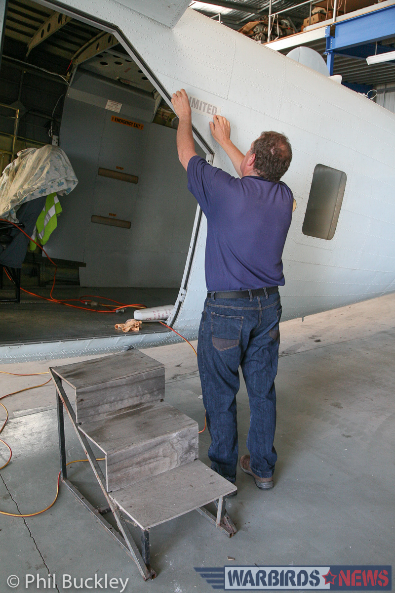 Richard Thompson applying the 'LIMITED' stencil to the fuselage near the cargo door. (photo by Phil Buckley)