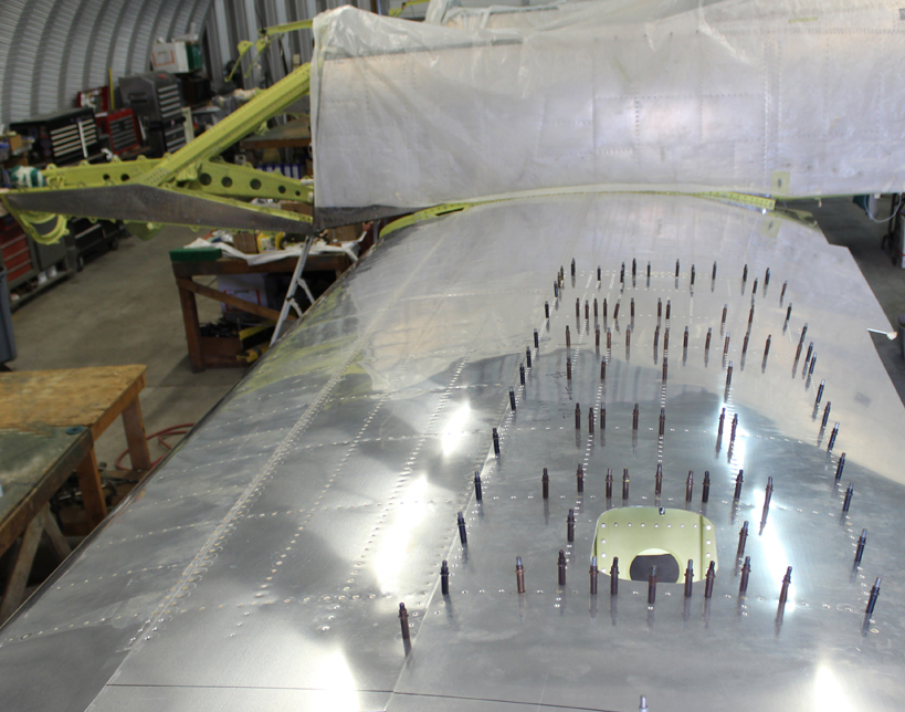 Final riveting of the left-hand wing top skins. (photo via Tom Reilly)