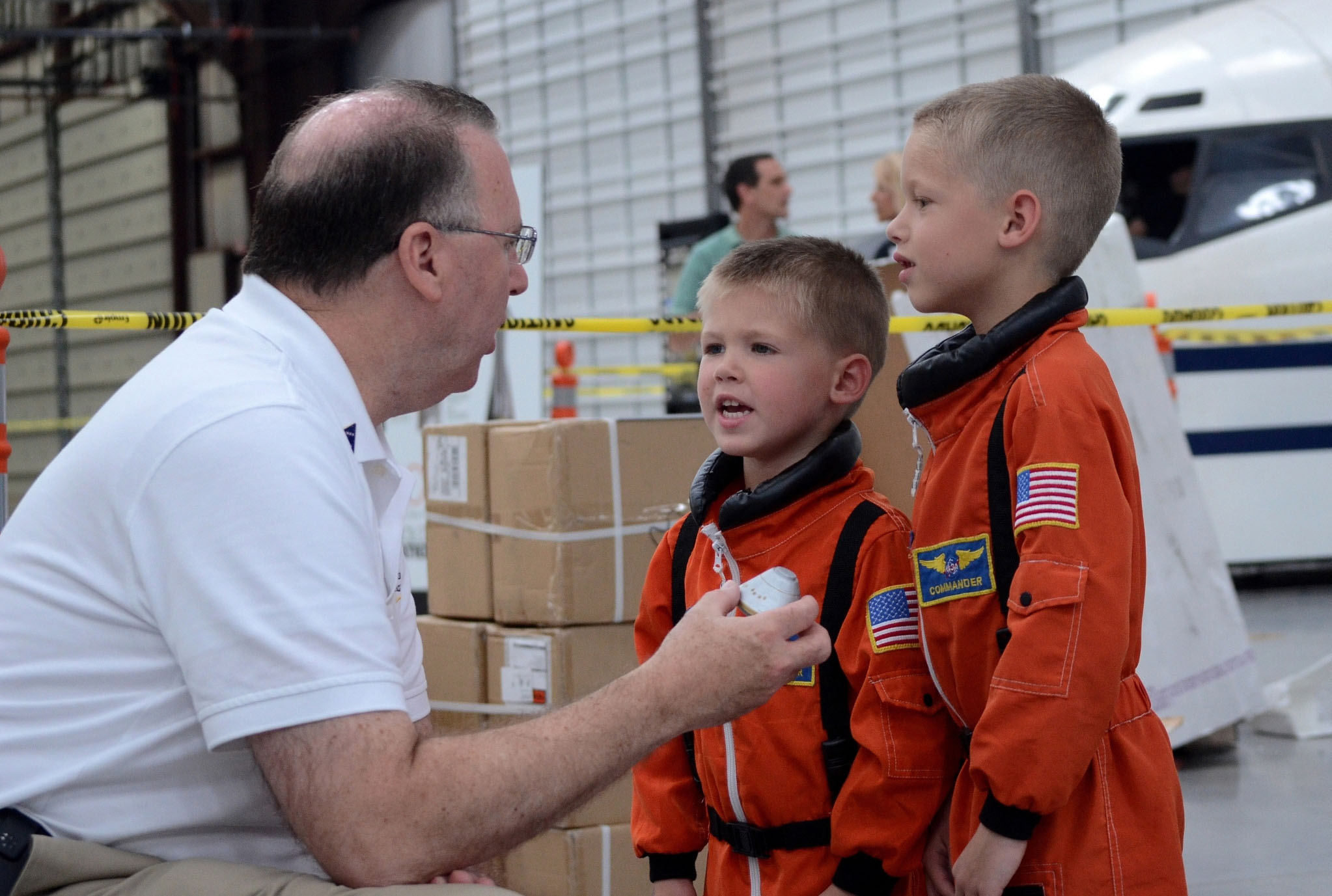  Brothers and future astornauts Galeb (4 years old) and Aiden (7 years old) Mann discuss Orion’s journey with a Lockheed Martin team member. Photo by John Bezosky Jr.
