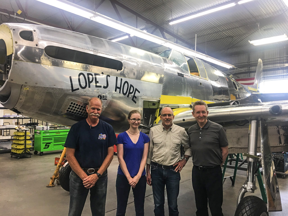 (L-R)Warren Pietsch of Texas Flying Legends Museum, Laura Lopez, Bruce Eames of Texas Flying Legends Museum, and Dr. Donald Lopez Jr. together in front of Lope’s Hope 3rd in the AirCorps restoration shop. (photo via AirCorps Aviation)