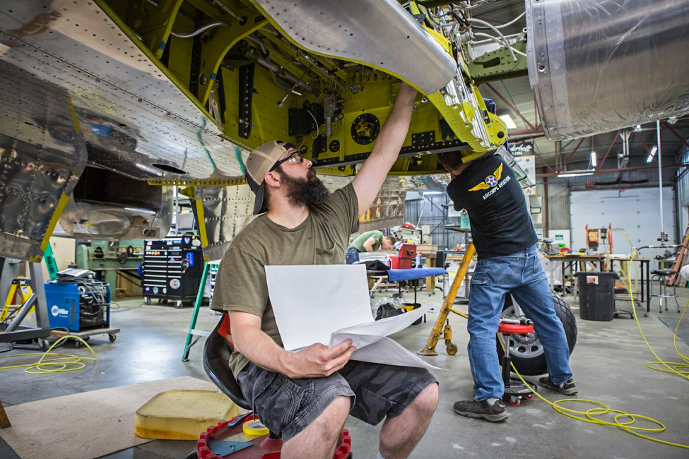 Randy checks the engineering drawings as he looks over gear well installations. (photo via AirCorps Aviation)