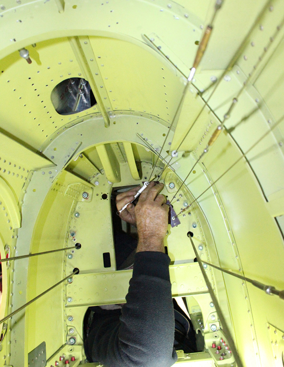 Tom Reilly's hands adjusting the tension on one of the many rudder/elevator/trim control cables a rear fuselage. (photo via Tom Reilly)