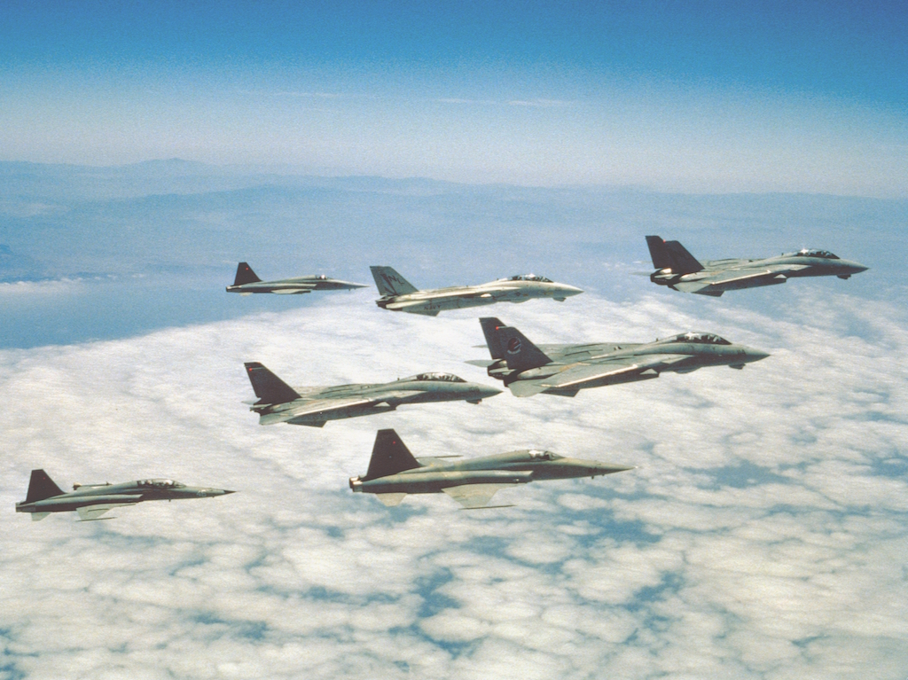 A formation of F-14A Tomcats of Fighter Squadrons VF-51 Screaming Eagles and VF-111 Sundowners, and F-5E/F Tiger II's of the Navy Fighter Weapons School. These units represented a vital part of the U.S. Navy's participation in the 1986 feature-film "TOPGUN", providing the aerial dogfighting sequences that were a defining trademark of this movie. Note the fictitious markings on the tail of at least one of the F-14's.