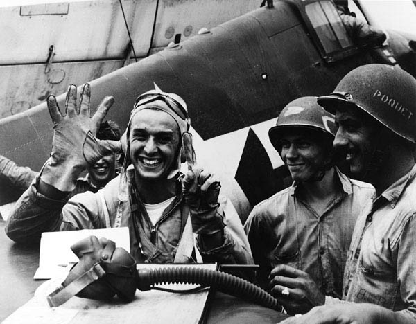 Alex Vraciu holding up five fingers and a thumb, representing the six Japanese dive bombers he had just shot down during battle on June 19th, 1944. (US Navy photo)