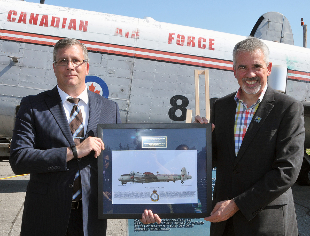 The curator of the National Air Force Museum of Canada, Kevin Windsor (left), presents Edmundston mayor Cyrille Simard with an artist’s concept of how KB882 will appear following its restoration. (Photo by Warrant Officer Fran Gaudet DND)