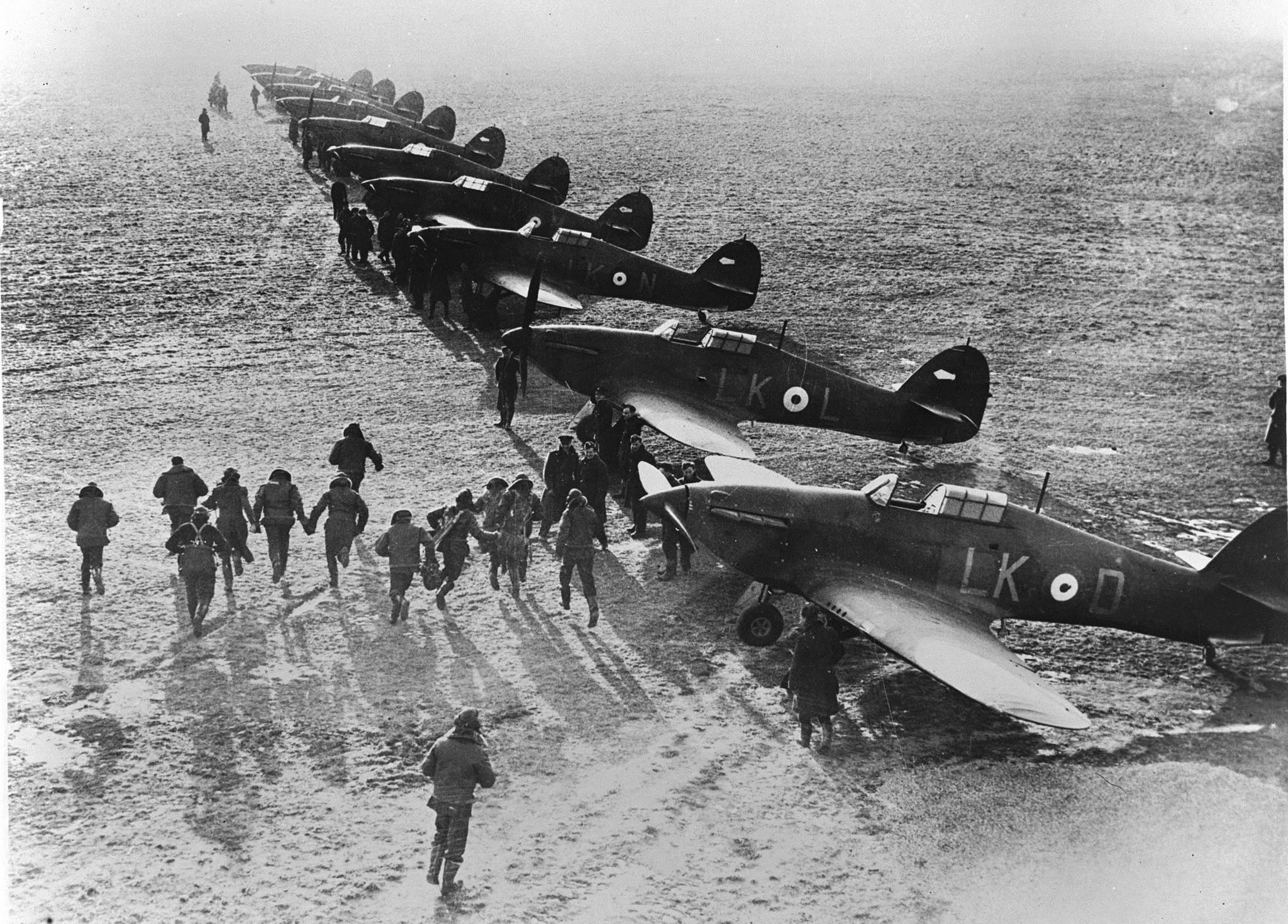 Pilots scramble for their Hawker Hurricane fighters at an airfield in England to tackle the Luftwaffe during the Battle of Britain. (photo via RCAF)